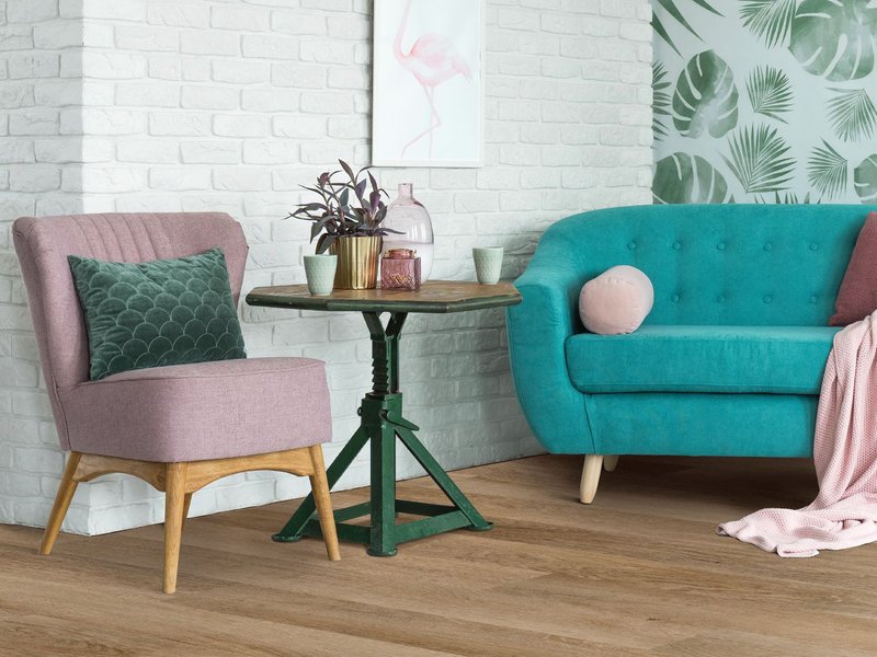 pink arm chair and teal couch on wood look flooring - B D Flooring Inc