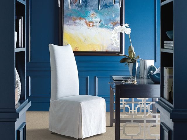 white covered chair in room with blue walls and colorful painting - B D Flooring Inc